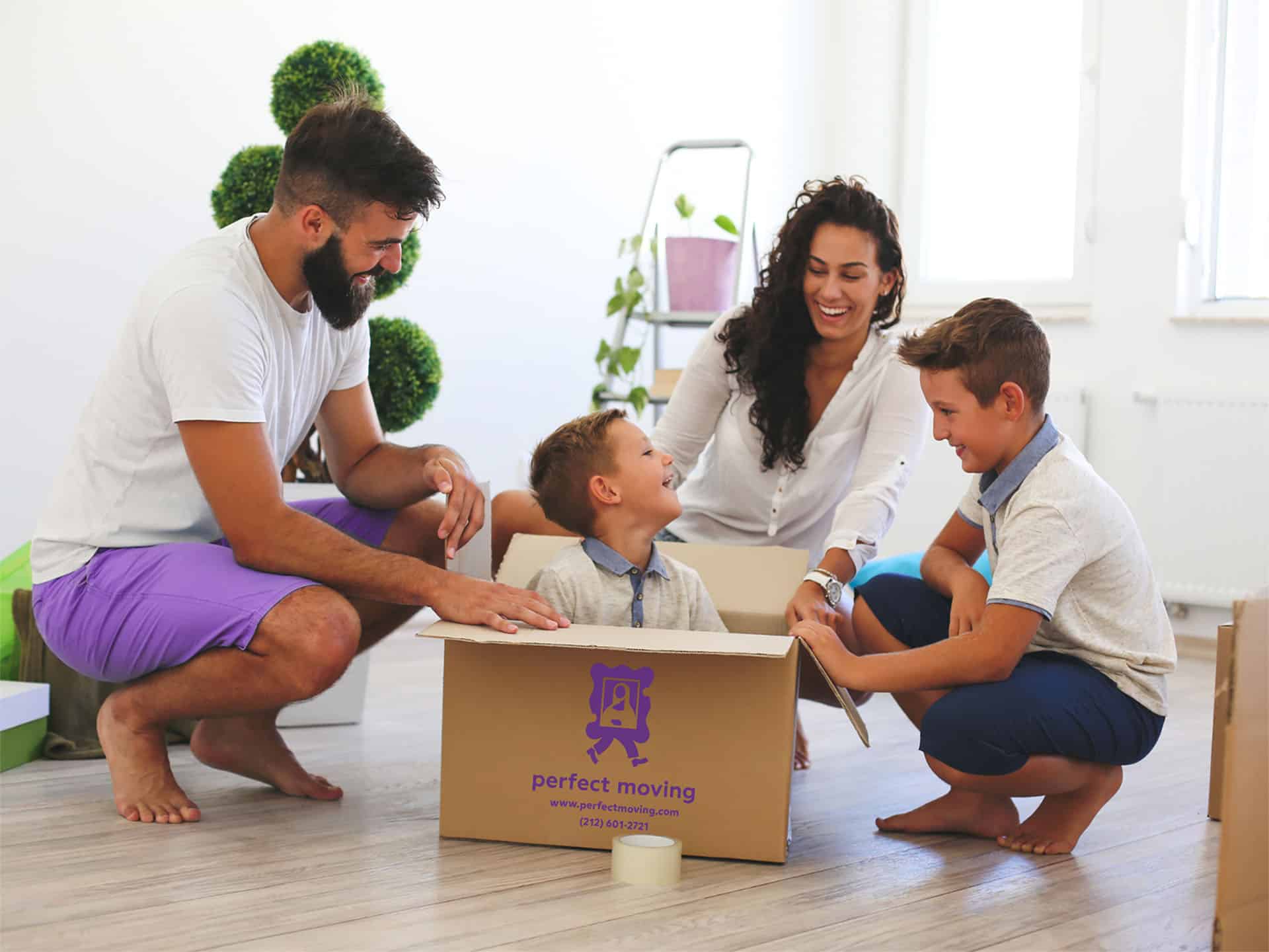 A family of four smiling around an open Perfect Moving box in a bright room
