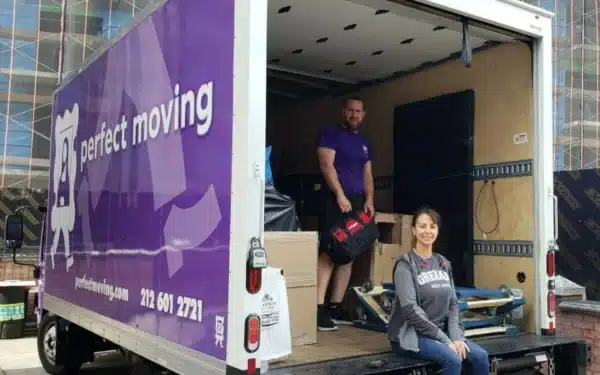 A Perfect Moving mover inside an open Perfect Moving truck with boxes, and a woman on the lift gate